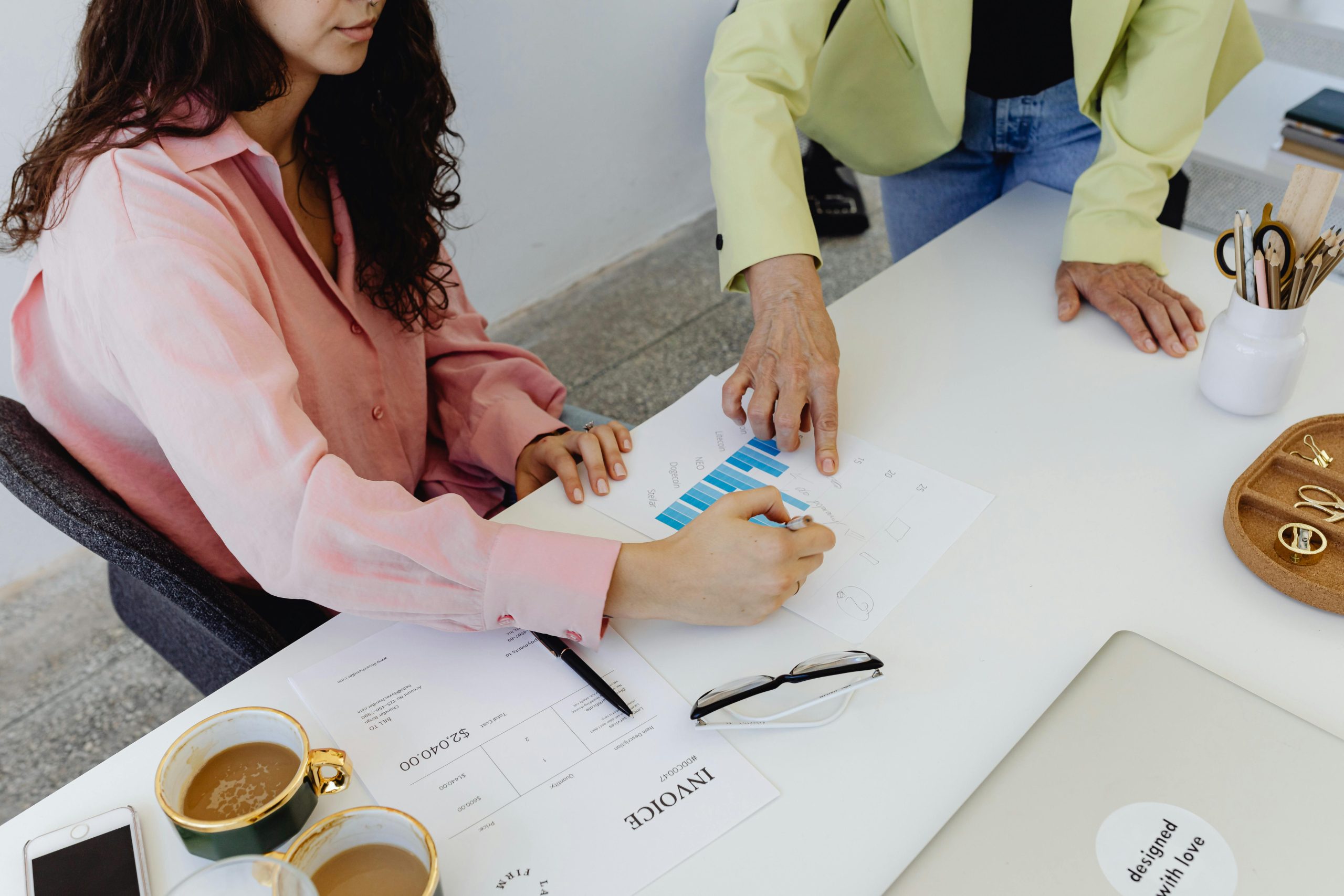 Two colleagues work together on financial graphs, promoting teamwork in a modern office setting.